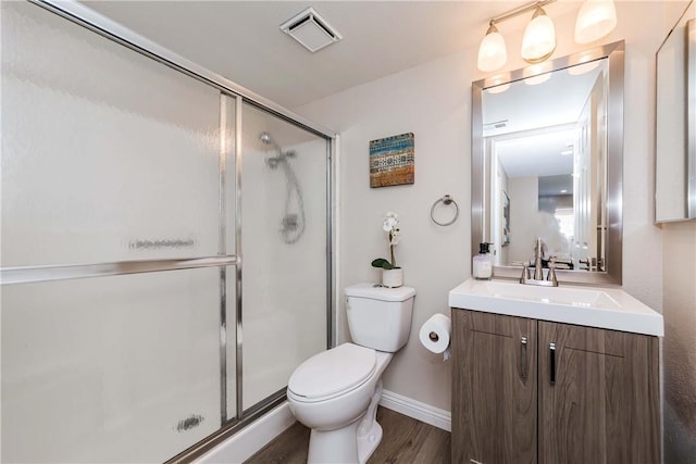 bathroom featuring hardwood / wood-style floors, vanity, toilet, and a shower with door