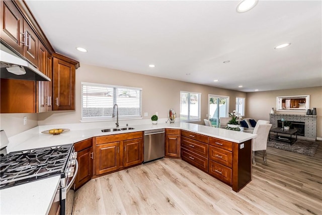 kitchen with appliances with stainless steel finishes, sink, kitchen peninsula, and light hardwood / wood-style floors