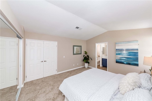 bedroom featuring lofted ceiling, ensuite bath, and carpet flooring