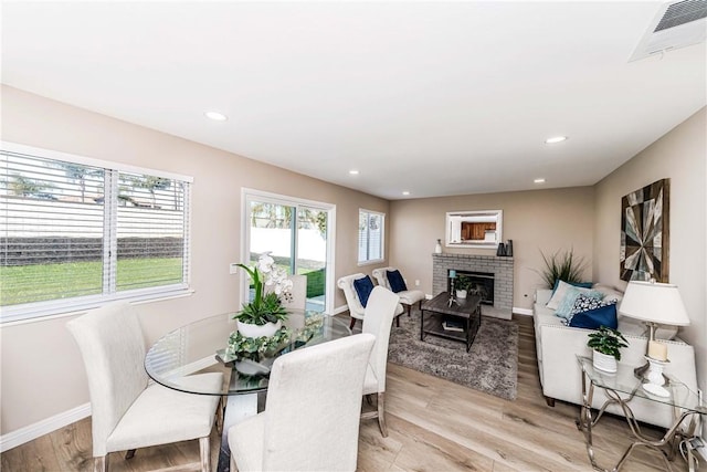 dining space with a brick fireplace and light wood-type flooring