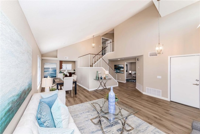 living room with a notable chandelier, high vaulted ceiling, and wood-type flooring