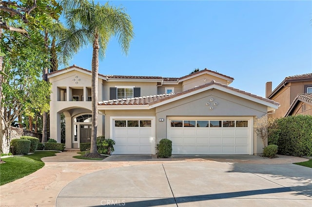 mediterranean / spanish house featuring a garage, a tile roof, driveway, and stucco siding