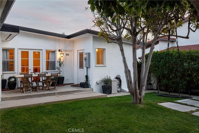 back of property with a yard and stucco siding