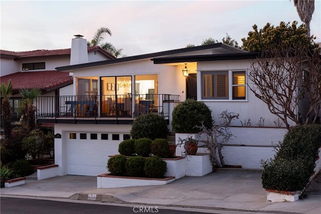 view of front facade with driveway, a chimney, an attached garage, and stucco siding