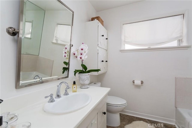 bathroom with toilet, baseboards, a bathtub, and vanity