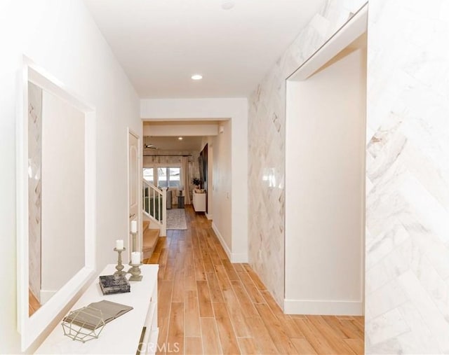 hallway featuring recessed lighting, light wood-style flooring, baseboards, and stairs