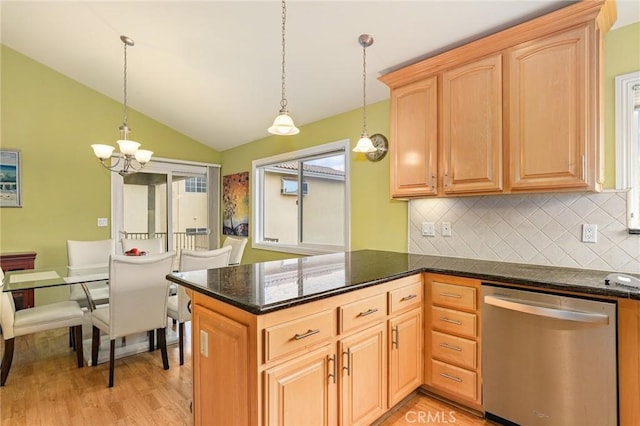 kitchen featuring kitchen peninsula, lofted ceiling, decorative light fixtures, dishwasher, and dark stone countertops