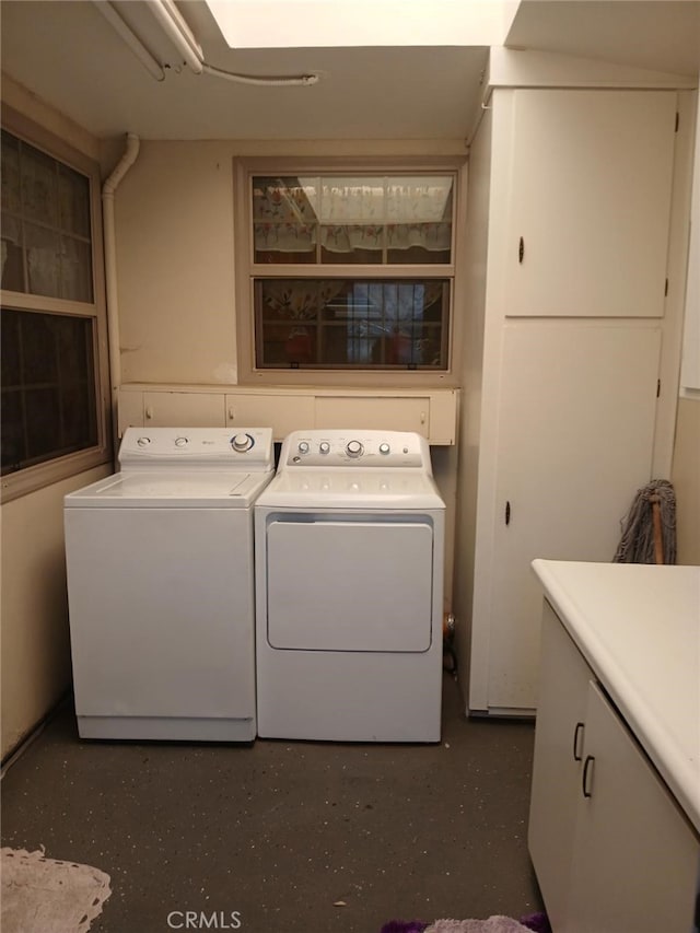 clothes washing area featuring washer and clothes dryer and cabinets