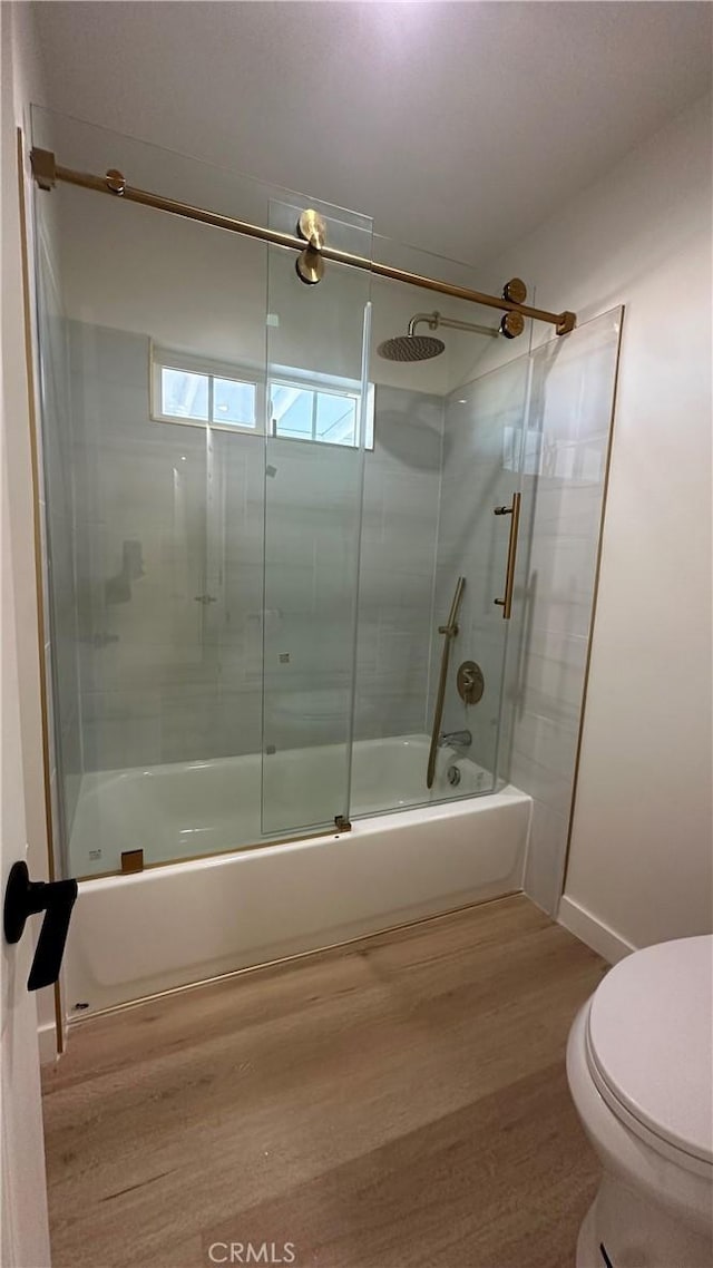 bathroom with toilet, hardwood / wood-style floors, and bath / shower combo with glass door