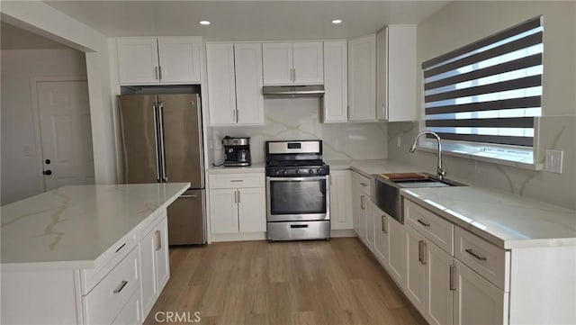 kitchen featuring sink, stainless steel appliances, white cabinetry, and light stone counters