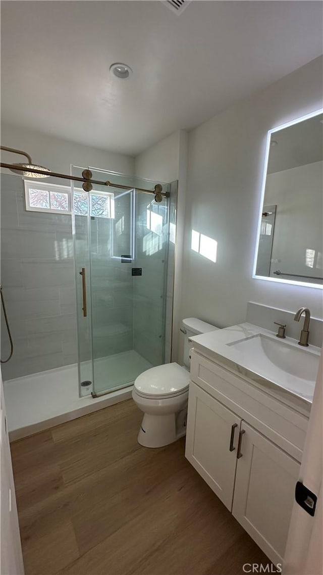 bathroom with toilet, wood-type flooring, an enclosed shower, and vanity