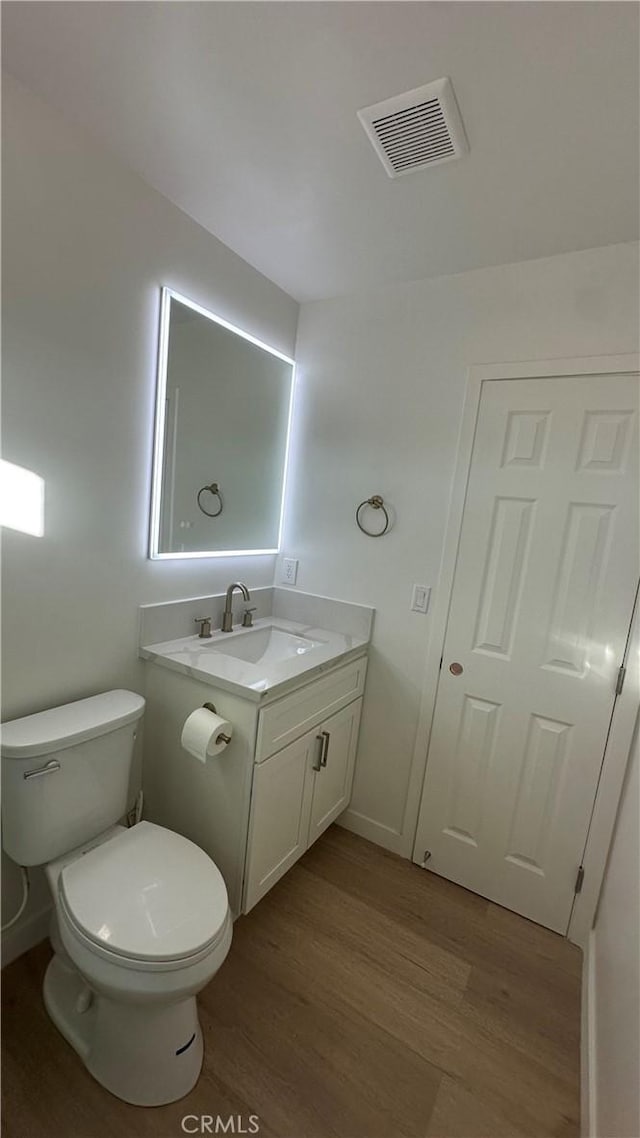 bathroom with toilet, vanity, and hardwood / wood-style floors