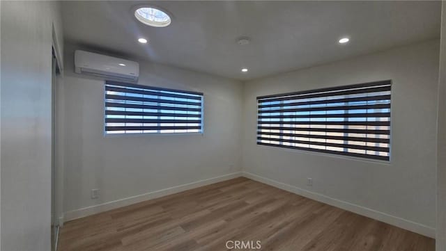 spare room featuring an AC wall unit and hardwood / wood-style floors