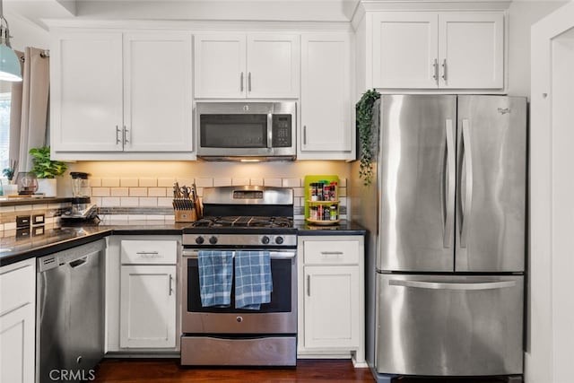 kitchen with stainless steel appliances, dark countertops, dark wood finished floors, and white cabinetry