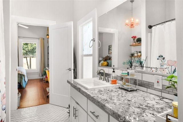 full bathroom with a chandelier, tile patterned flooring, vanity, and decorative backsplash