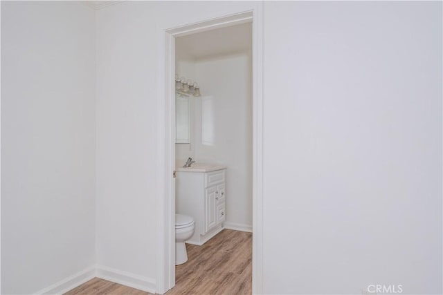 bathroom with baseboards, vanity, toilet, and wood finished floors