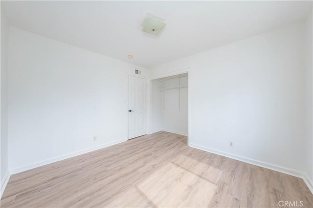 spare room featuring baseboards, visible vents, and light wood-style floors