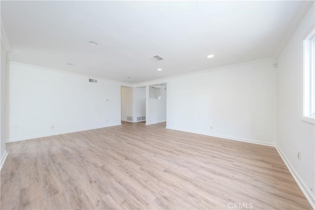 spare room with light wood-style floors, visible vents, and ornamental molding