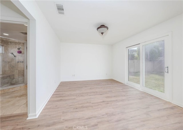 empty room featuring light wood-type flooring, visible vents, and baseboards