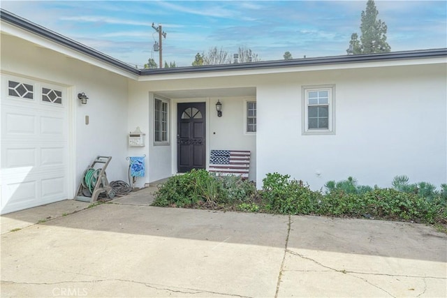 property entrance with a garage and stucco siding