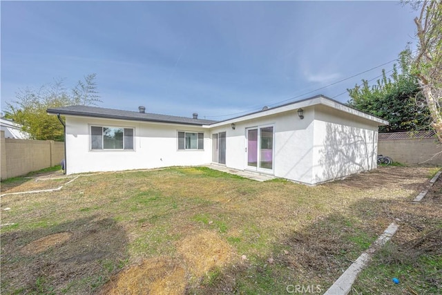 back of property featuring a yard, a fenced backyard, and stucco siding