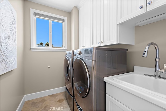 washroom featuring cabinet space, baseboards, a sink, and washing machine and clothes dryer