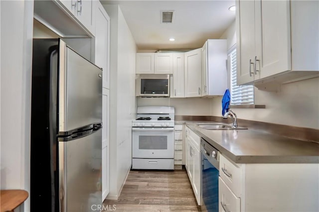 kitchen featuring white cabinets, light wood-type flooring, stainless steel appliances, and sink