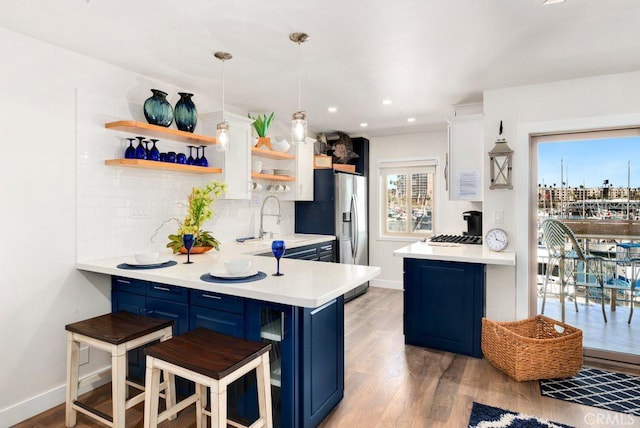 kitchen featuring kitchen peninsula, blue cabinetry, a kitchen bar, and decorative light fixtures