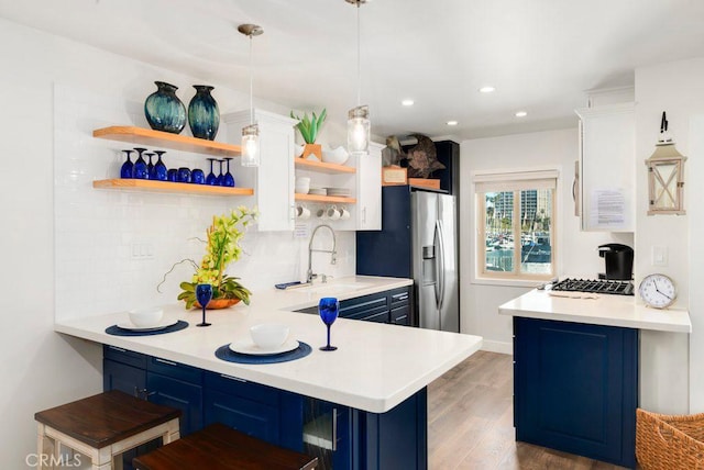 kitchen with blue cabinetry, pendant lighting, a breakfast bar, and kitchen peninsula