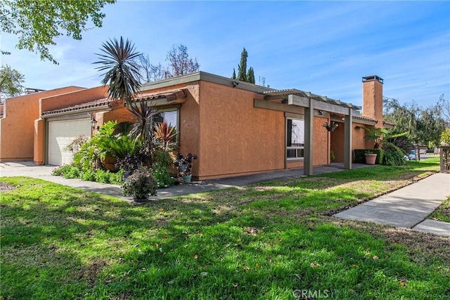 view of front of house with an attached garage, a front lawn, and stucco siding