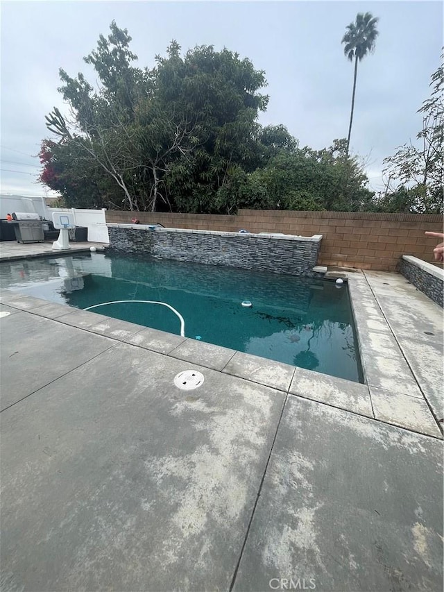 view of swimming pool with a grill, fence, and a fenced in pool