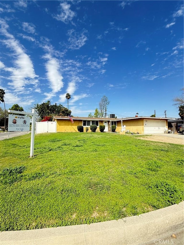 ranch-style house featuring a front yard, concrete driveway, and an attached garage