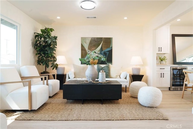 living area with beverage cooler, recessed lighting, light wood-style floors, and a wealth of natural light