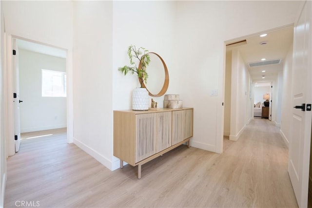 corridor featuring visible vents, baseboards, and light wood-style flooring