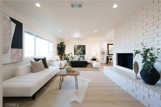 living room with visible vents, recessed lighting, a fireplace, and light wood-style floors