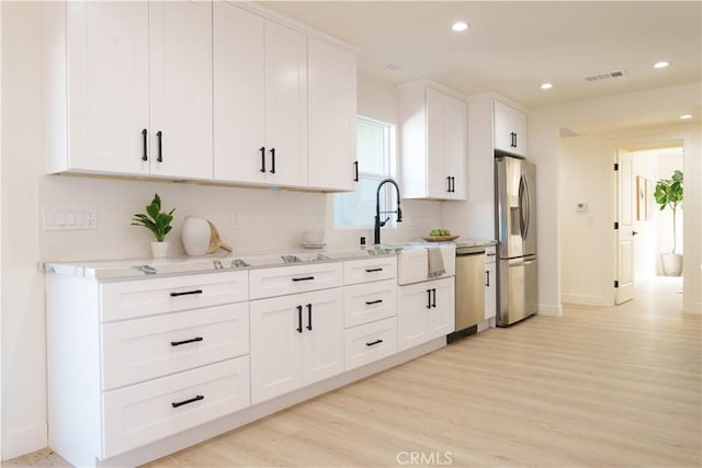 kitchen featuring visible vents, light wood-style flooring, white cabinetry, and stainless steel appliances