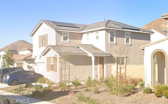 view of front facade with a mountain view and solar panels