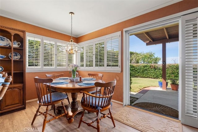 dining room with light wood-style floors, crown molding, baseboards, and a notable chandelier