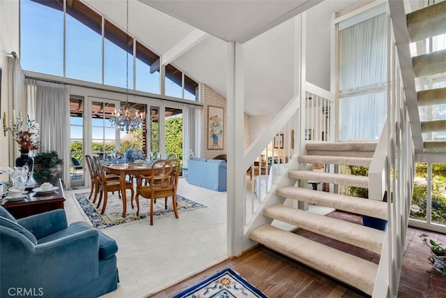 stairs featuring an inviting chandelier, high vaulted ceiling, wood finished floors, and beamed ceiling