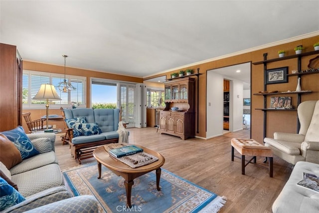 living area featuring baseboards, ornamental molding, light wood-type flooring, and an inviting chandelier