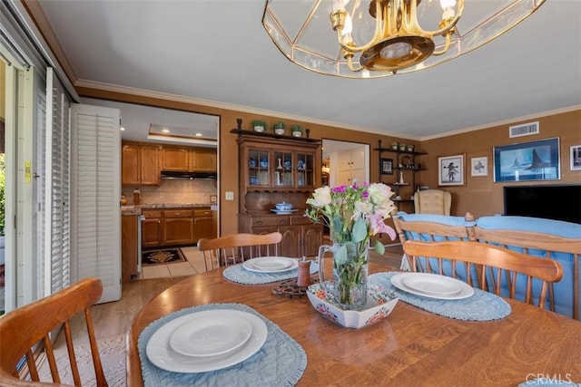 dining space with light tile patterned flooring, visible vents, crown molding, and an inviting chandelier