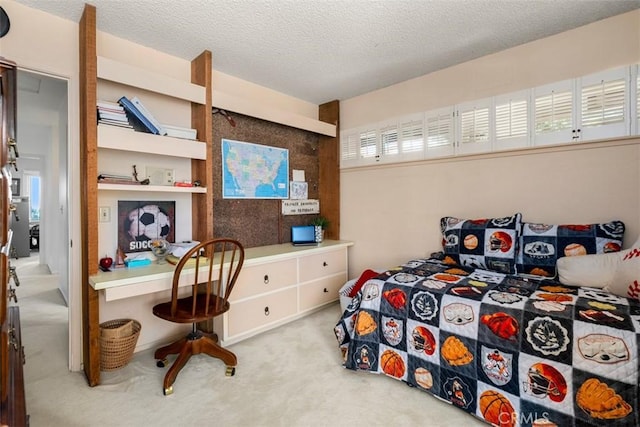 bedroom featuring a textured ceiling, built in desk, and light colored carpet