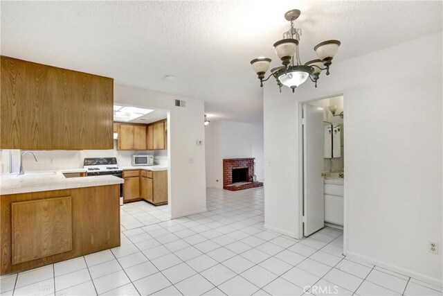 2061 W Redlands Blvd Unit 8C, Redlands, CA 92373 - kitchen featuring white appliances, brown cabinets, tile counters, a fireplace, and a chandelier