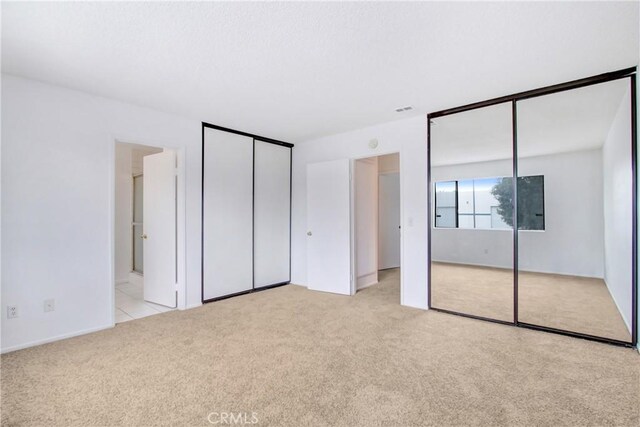 2061 W Redlands Blvd Unit 8C, Redlands, CA 92373 - unfurnished bedroom featuring two closets, light colored carpet, and connected bathroom