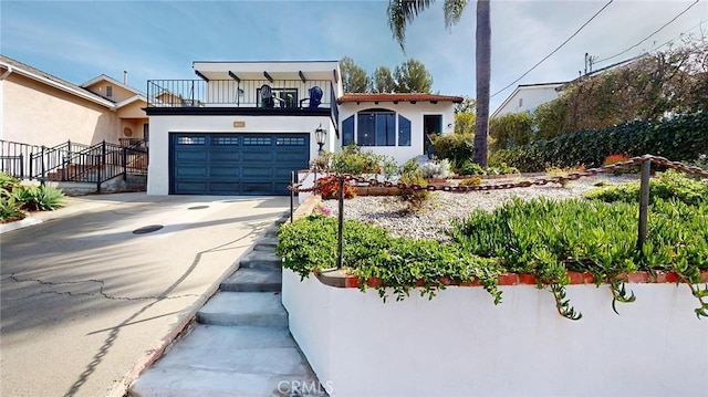 mediterranean / spanish house with a garage, concrete driveway, a balcony, and stucco siding