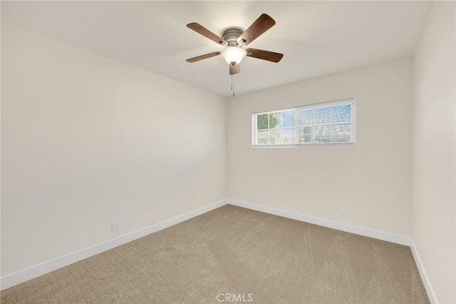 spare room featuring ceiling fan, light colored carpet, and baseboards