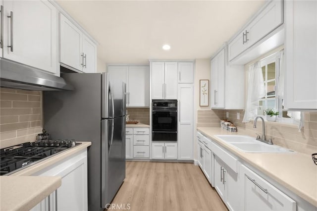 kitchen featuring a sink, white cabinets, under cabinet range hood, and black appliances