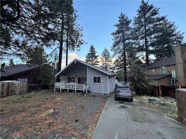 view of front of property with a deck, driveway, and fence