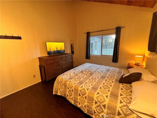 bedroom with vaulted ceiling, baseboards, and wood finished floors