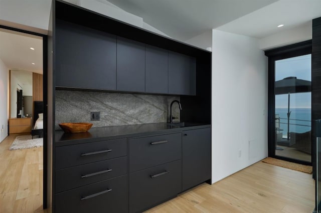 kitchen featuring a water view, sink, light hardwood / wood-style floors, and backsplash